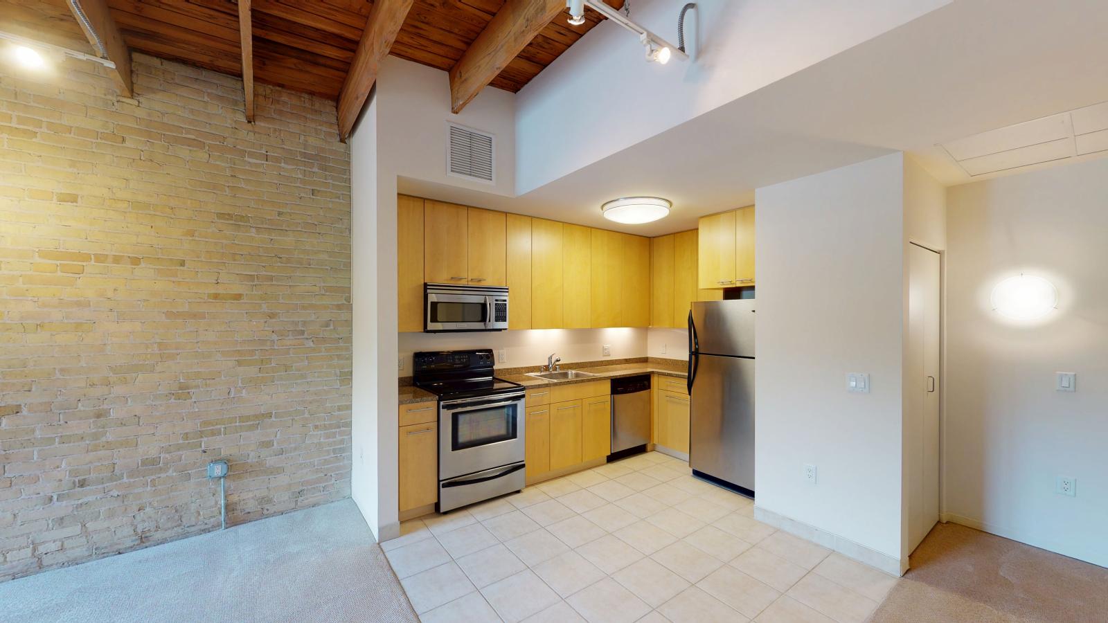 One bedroom apartment with an industrial style kitchen featuring granite countertops at Tobacco Lofts at The Yards in downtown Madison
