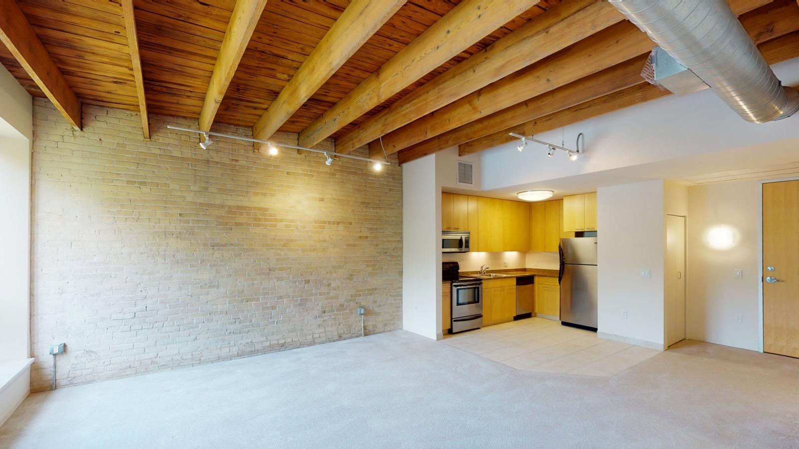One bedroom apartment with an industrial style kitchen featuring granite countertops at Tobacco Lofts at The Yards in downtown Madison