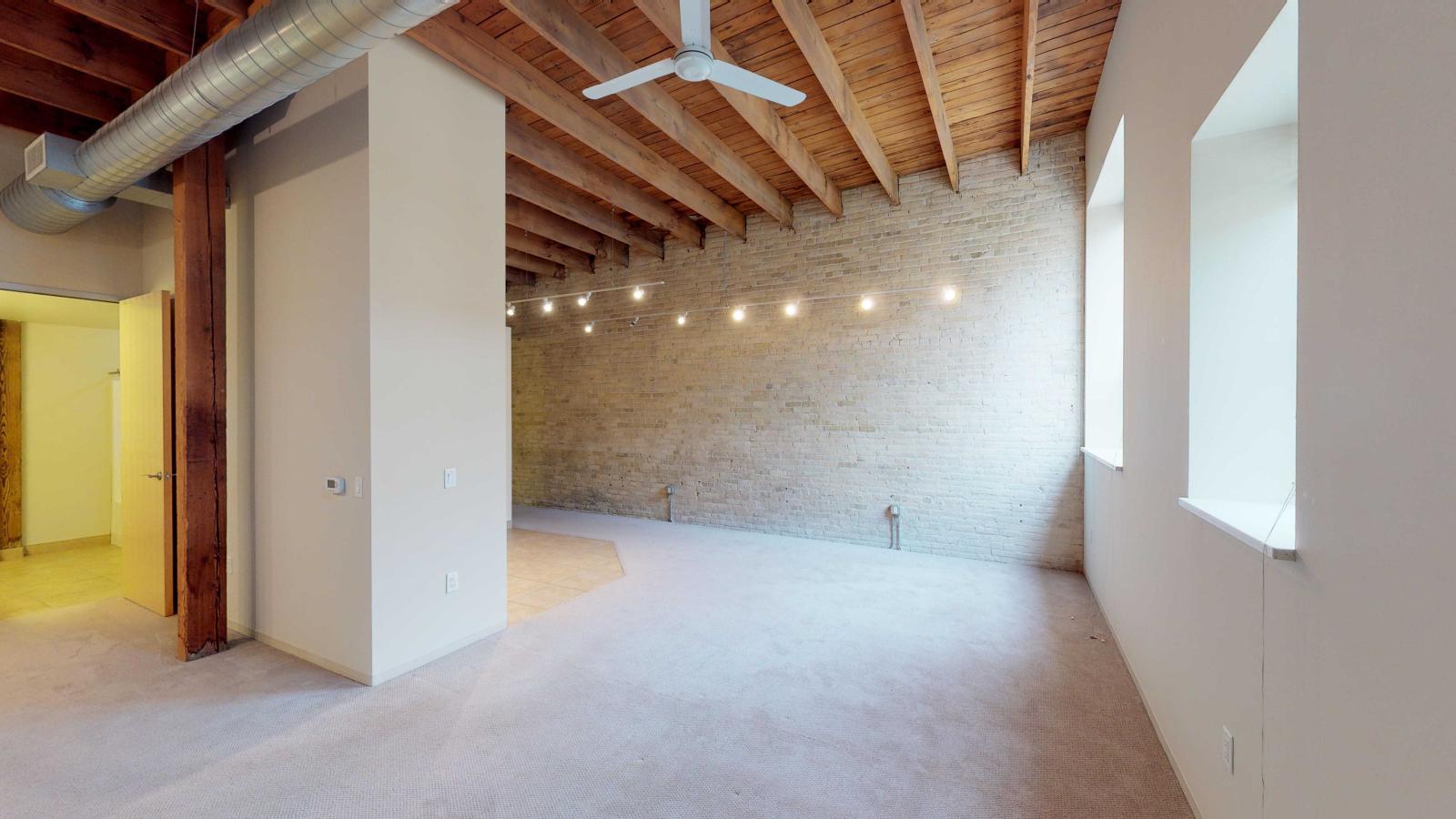 Open studio apartment with large windows and exposed brick at Tobacco Lofts