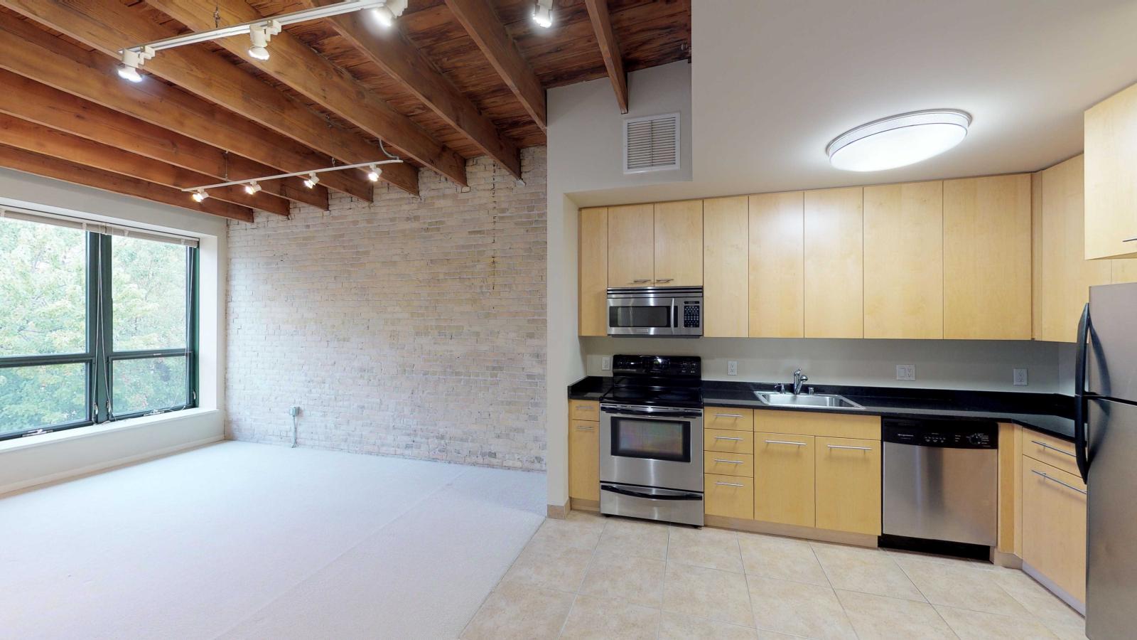 Studio apartment with an open-concept kitchen, modern appliances, and ample storage at Tobacco Lofts