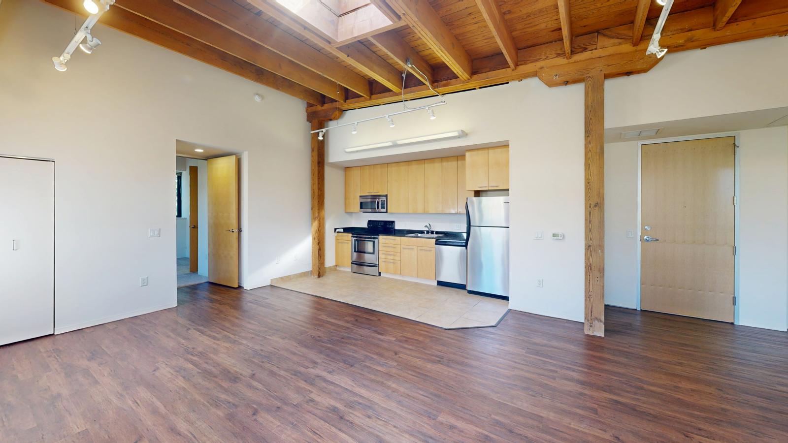 Two bedroom apartment with industrial style kitchen featuring stainless steel appliances at Tobacco Lofts at The Yards in downtown Madison