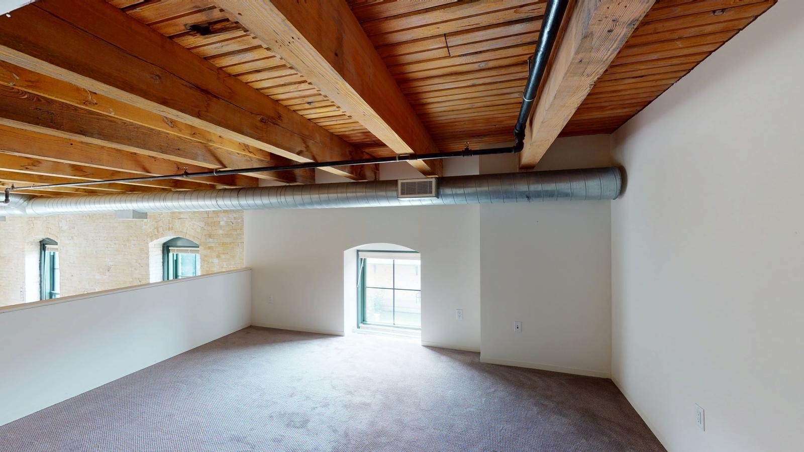 One bedroom loft style apartment with exposed heavy timber framing and open floor plan at Tobacco Lofts Apartment E202