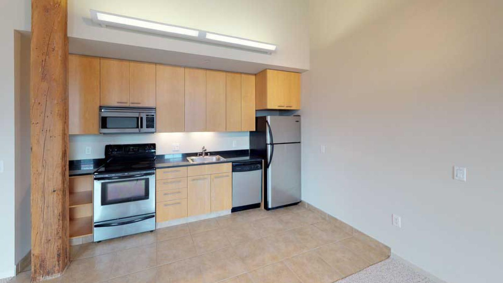 One bedroom apartment with an industrial style kitchen featuring granite countertops at Tobacco Lofts