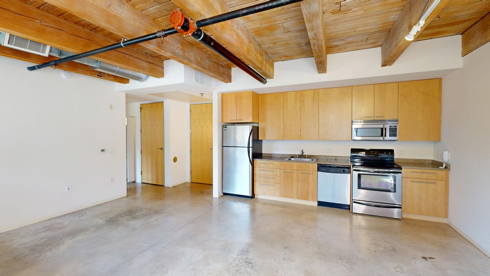 Industrial style one bedroom with polished concrete flooring and open concept design at Tobacco Lofts Apartment E103