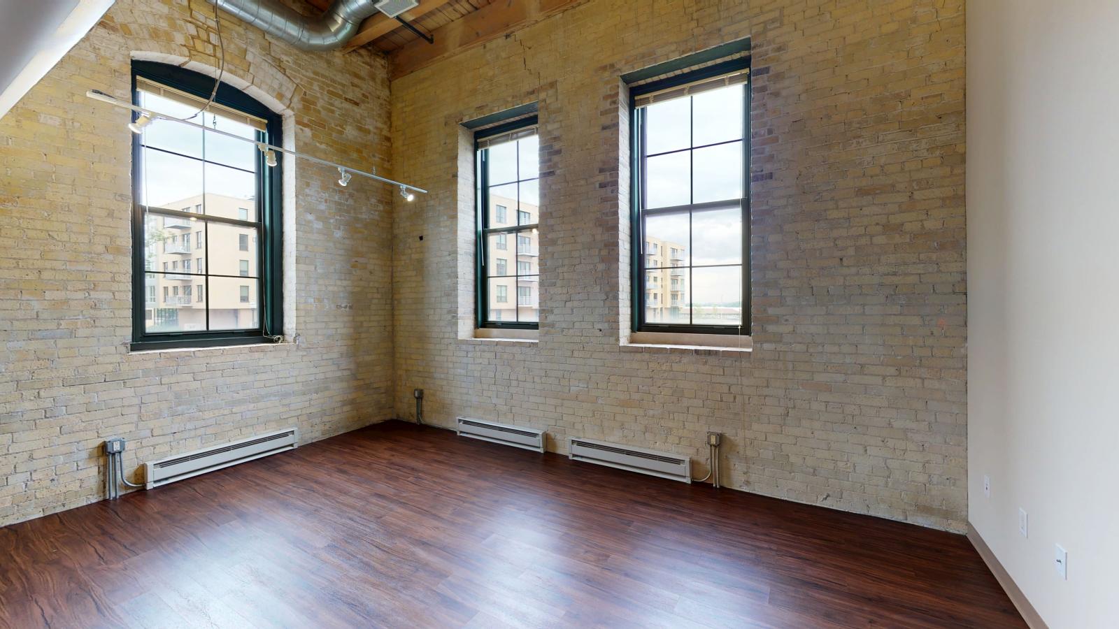 Lofted corner two bedroom with historic features, exposed brick, and partial lake view at Tobacco Lofts E201