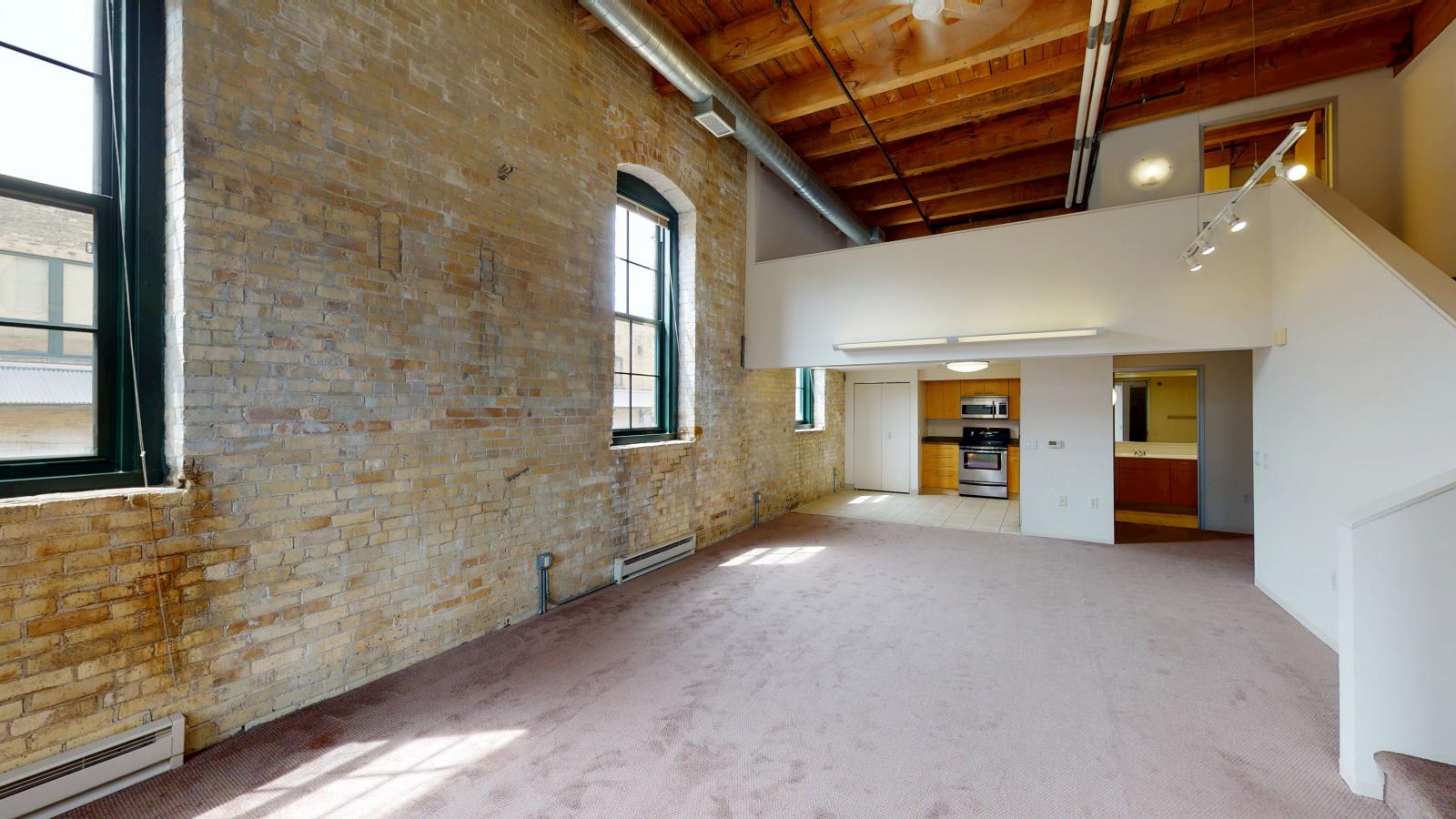 One bedroom loft apartment with exposed brick, timber beams, and high ceilings at Tobacco Lofts Apartment E202