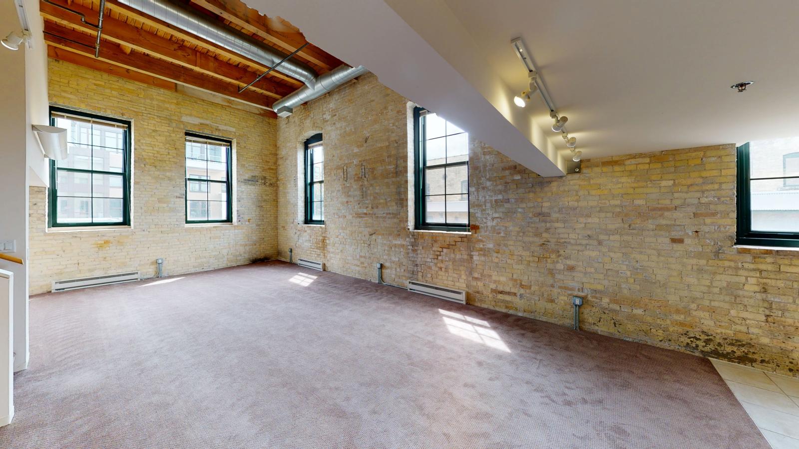 Industrial style one bedroom apartment with open concept design and natural light at Tobacco Lofts Apartment E202