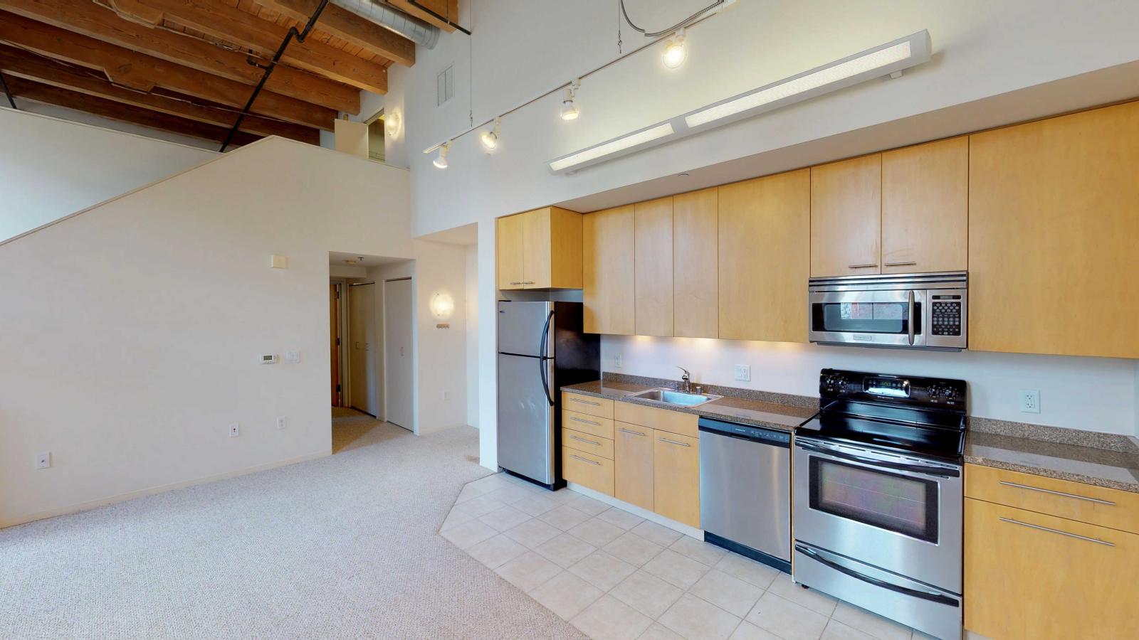 Two-bedroom apartment with industrial-style kitchen featuring stainless steel appliances at Tobacco Lofts