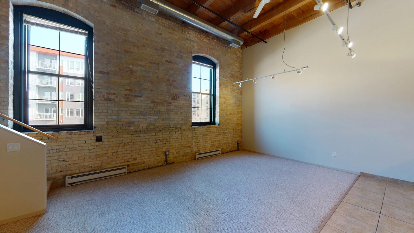 Two bedroom loft featuring large windows high ceilings and open loft style design at Tobacco Lofts Apartment E205