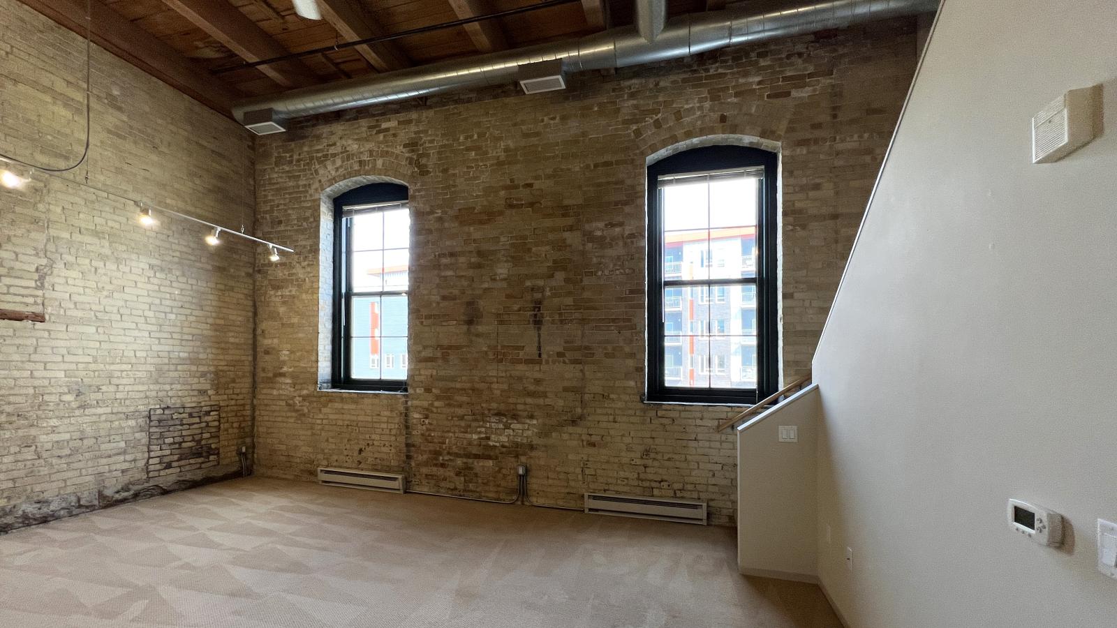 Two bedroom loft featuring large windows high ceilings and open loft style design at Tobacco Lofts Apartment E207