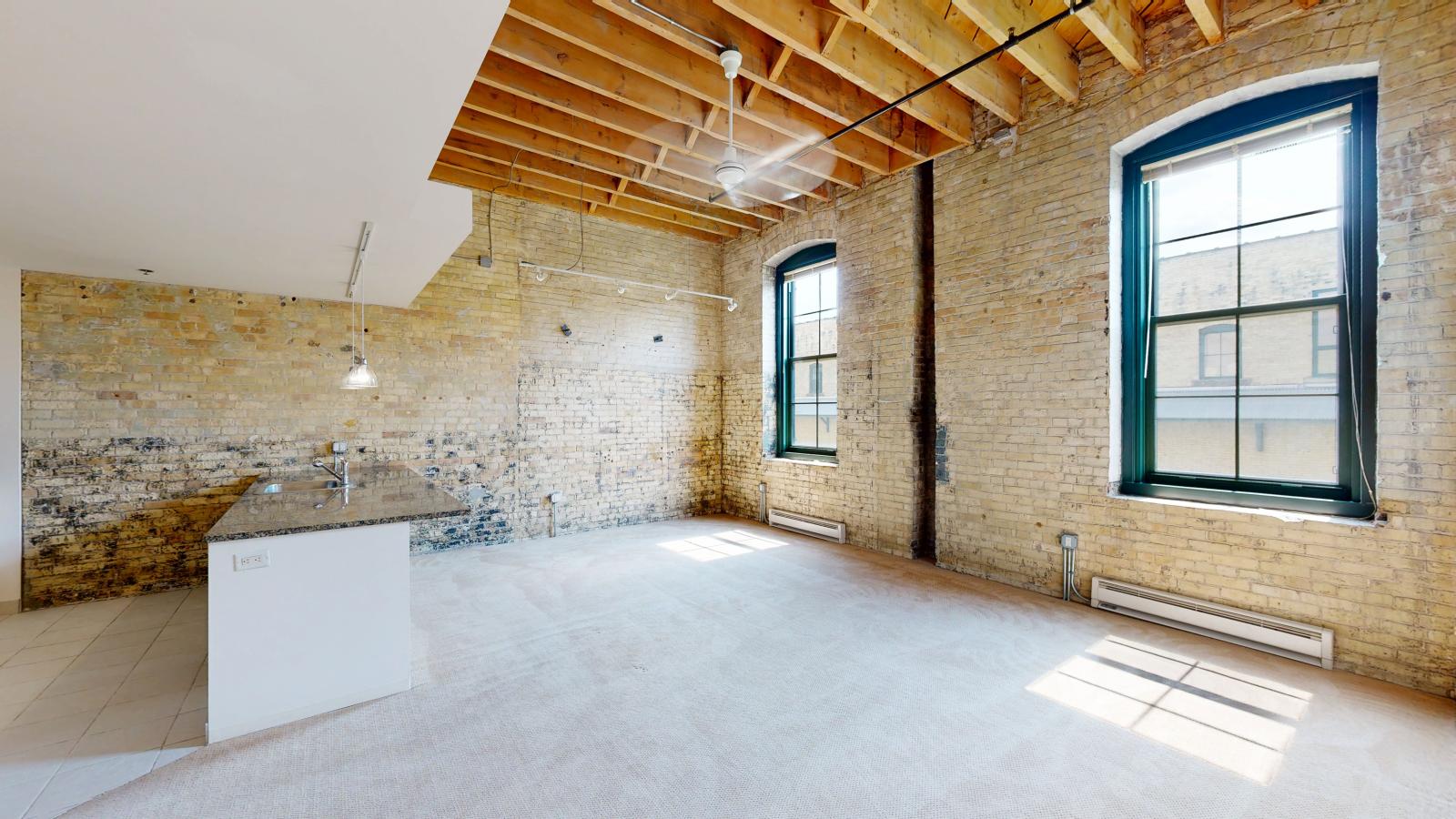 One bedroom loft apartment with exposed brick, timber beams, and high ceilings at Tobacco Lofts at The Yards in downtown Madison