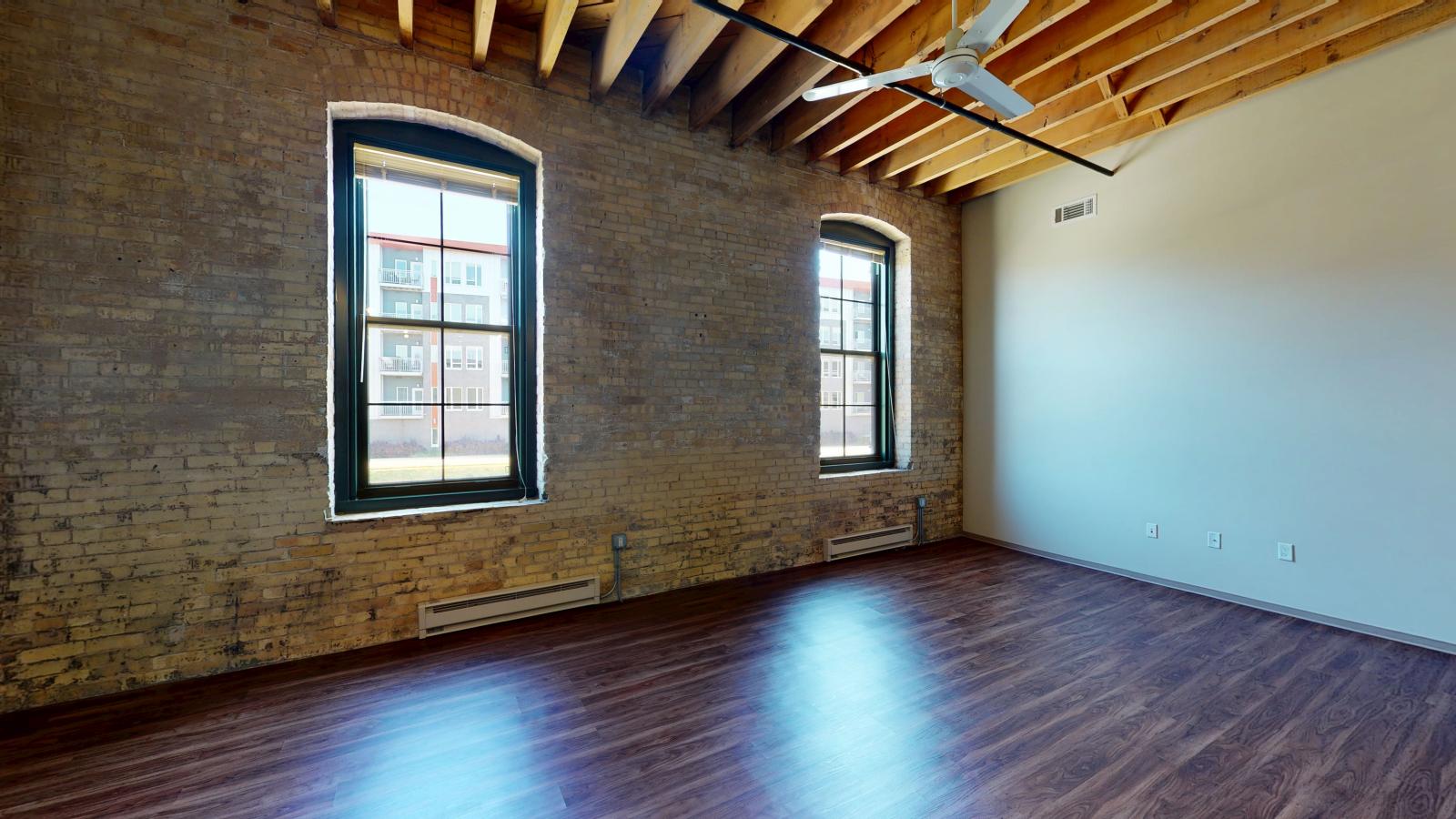 Bright and modern one bedroom apartment with large windows, exposed brick, and high ceilings at Tobacco Lofts at The Yards in downtown Madison