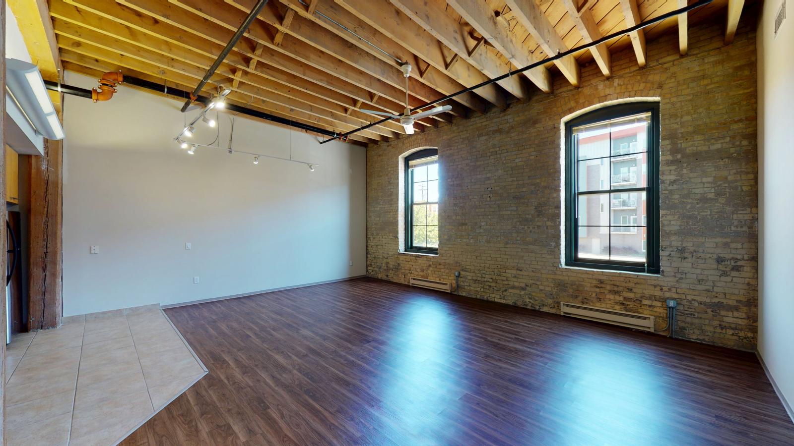 Bright and modern one bedroom apartment with large windows, exposed brick, and high ceilings at Tobacco Lofts at The Yards in downtown Madison