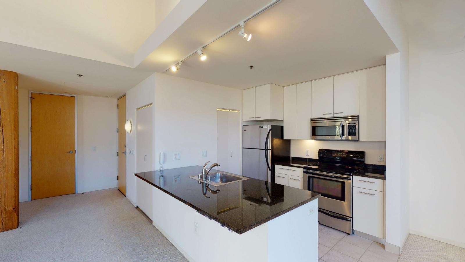 Two bedroom apartment featuring a modern kitchen with an open layout and ample counter space at Tobacco Lofts at The Yards in downtown Madison