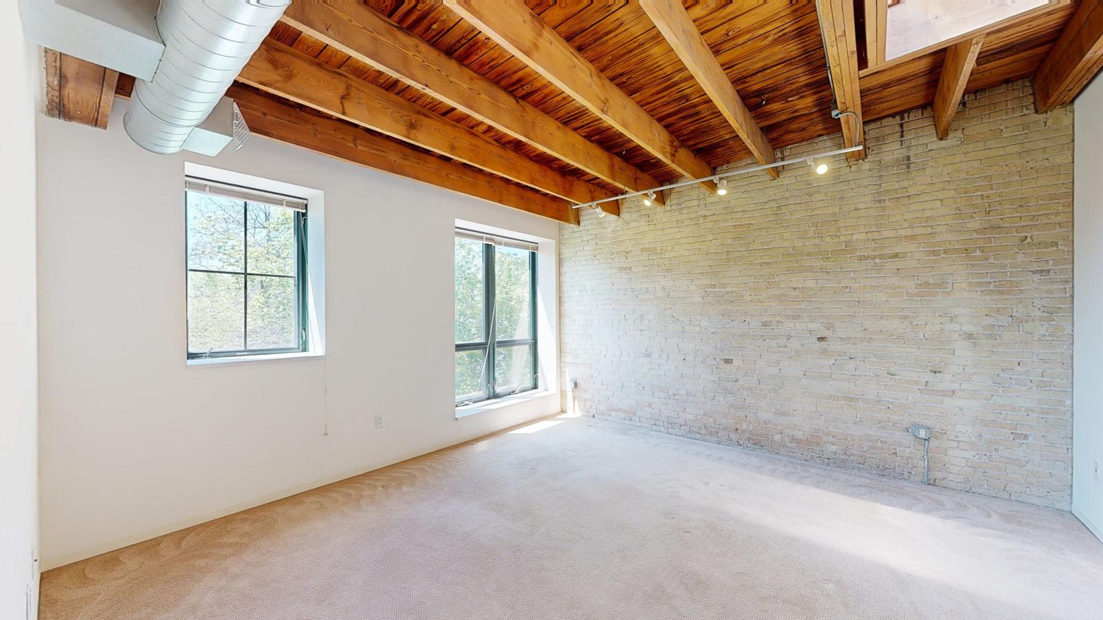 Bright and modern one bedroom apartment with large windows, exposed brick, and high ceilings at Tobacco Lofts at The Yards in downtown Madison