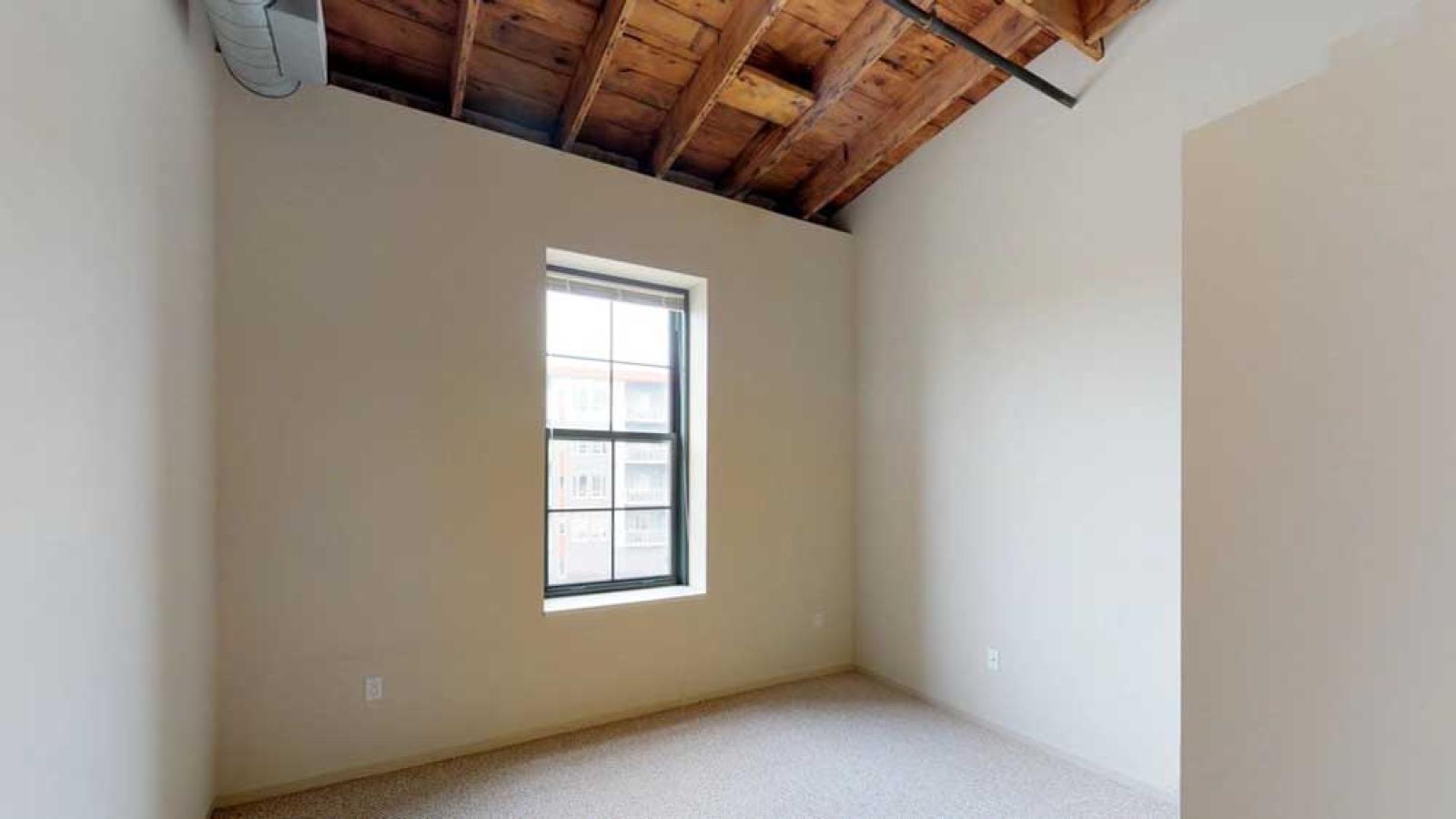 One bedroom with original wood ceilings and modern fixtures at Tobacco Lofts