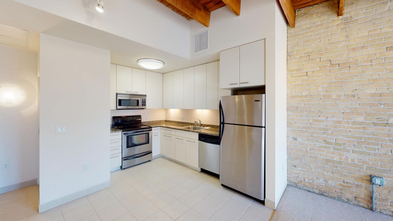 Studio apartment with an open-concept kitchen, modern appliances, and ample storage at Tobacco Lofts at The Yards in downtown Madison