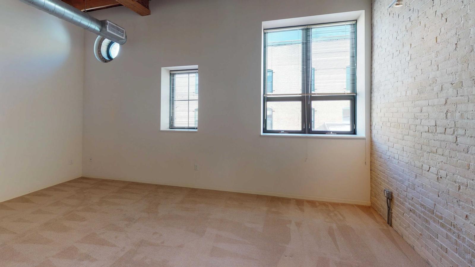 Loft-style studio apartment with exposed brick walls and restored timber framing at Tobacco Lofts