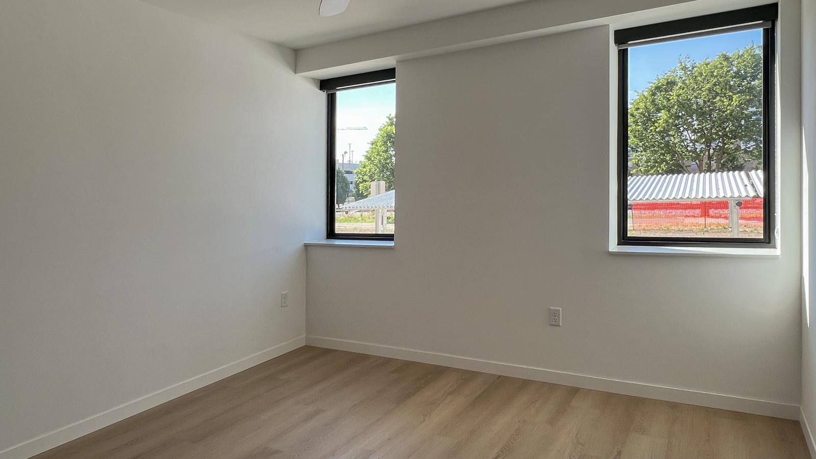 Bright one-bedroom apartment bedroom at The Irwin with large windows, natural light, luxury vinyl flooring, and modern minimalist finishes in Madison’s Willy Street neighborhood.
