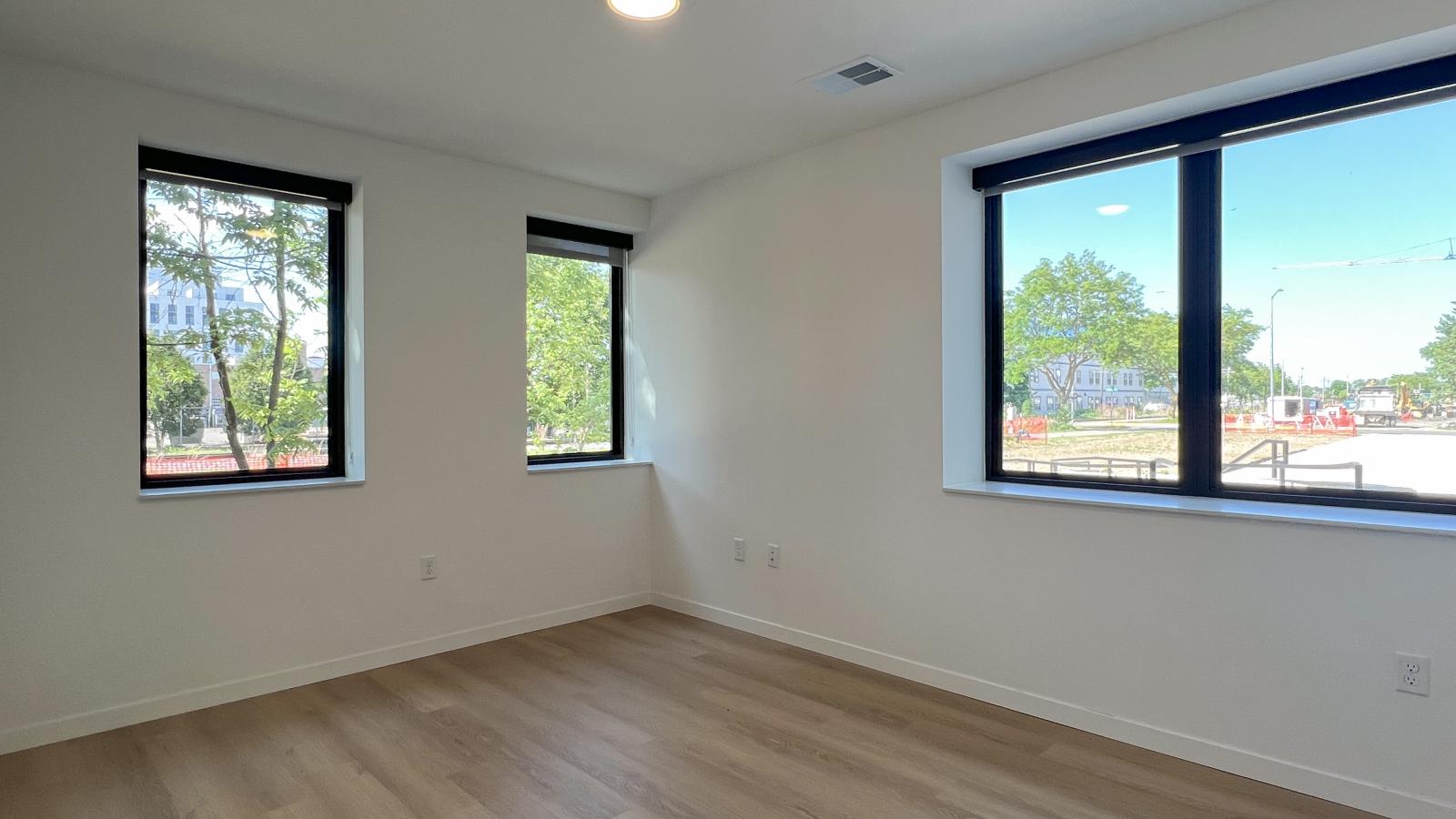 Bright guest bedroom at The Irwin Apartments with large black-framed windows, contemporary finishes, luxury vinyl flooring, and natural light in Madison, Wisconsin.