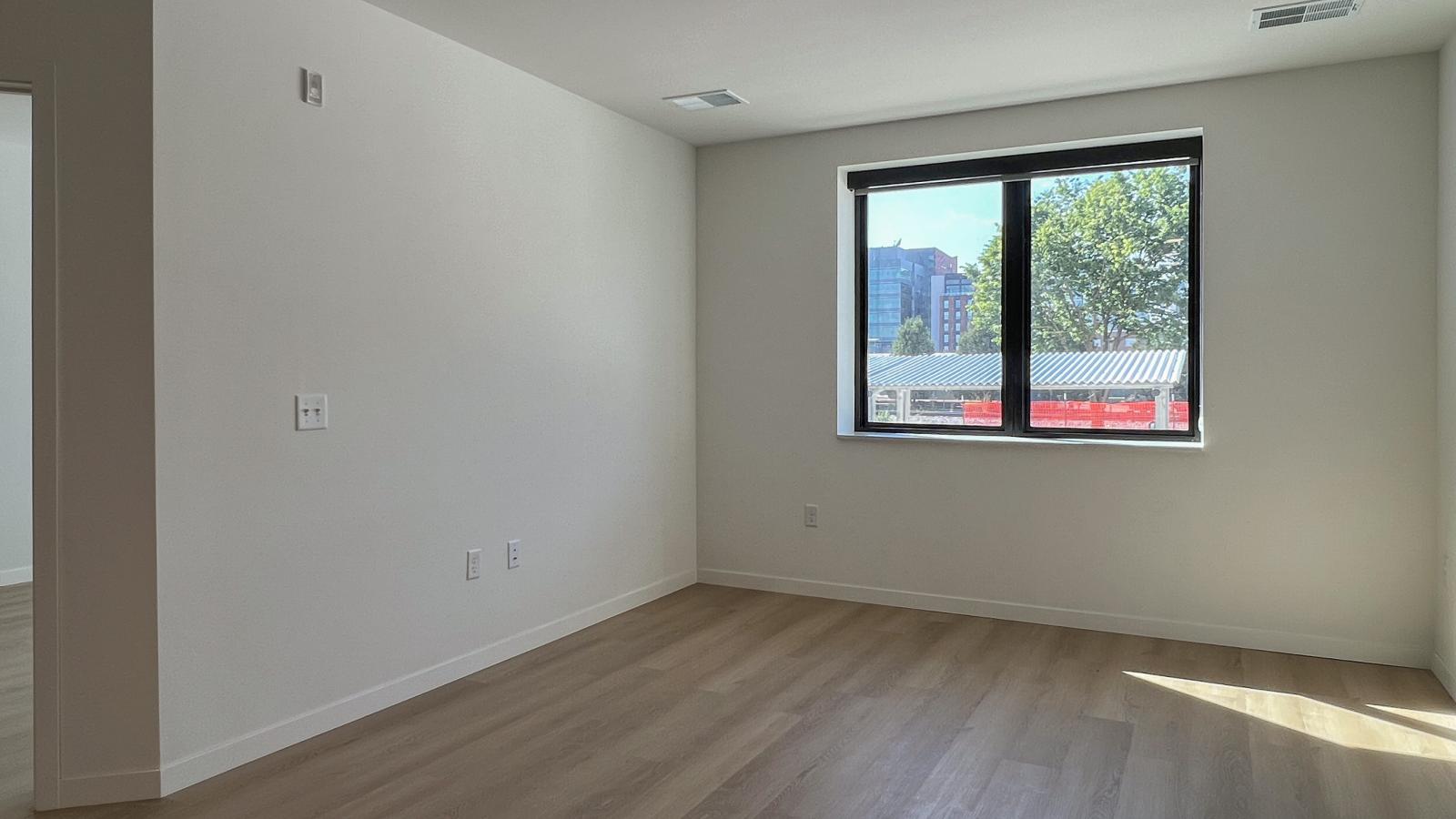 Bright one-bedroom apartment living space at The Irwin with large windows, natural light, luxury vinyl flooring, and modern minimalist finishes in Madison’s Willy Street neighborhood.