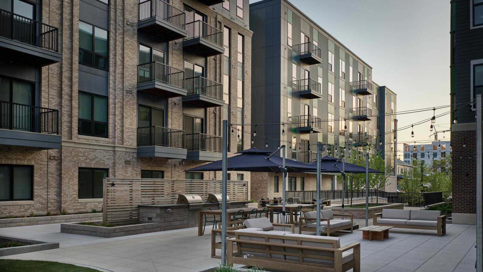 Landscaped courtyard at The Irwin featuring outdoor seating areas, gas grills, gathering spaces, and modern apartment surroundings in Madison’s Willy Street neighborhood.
