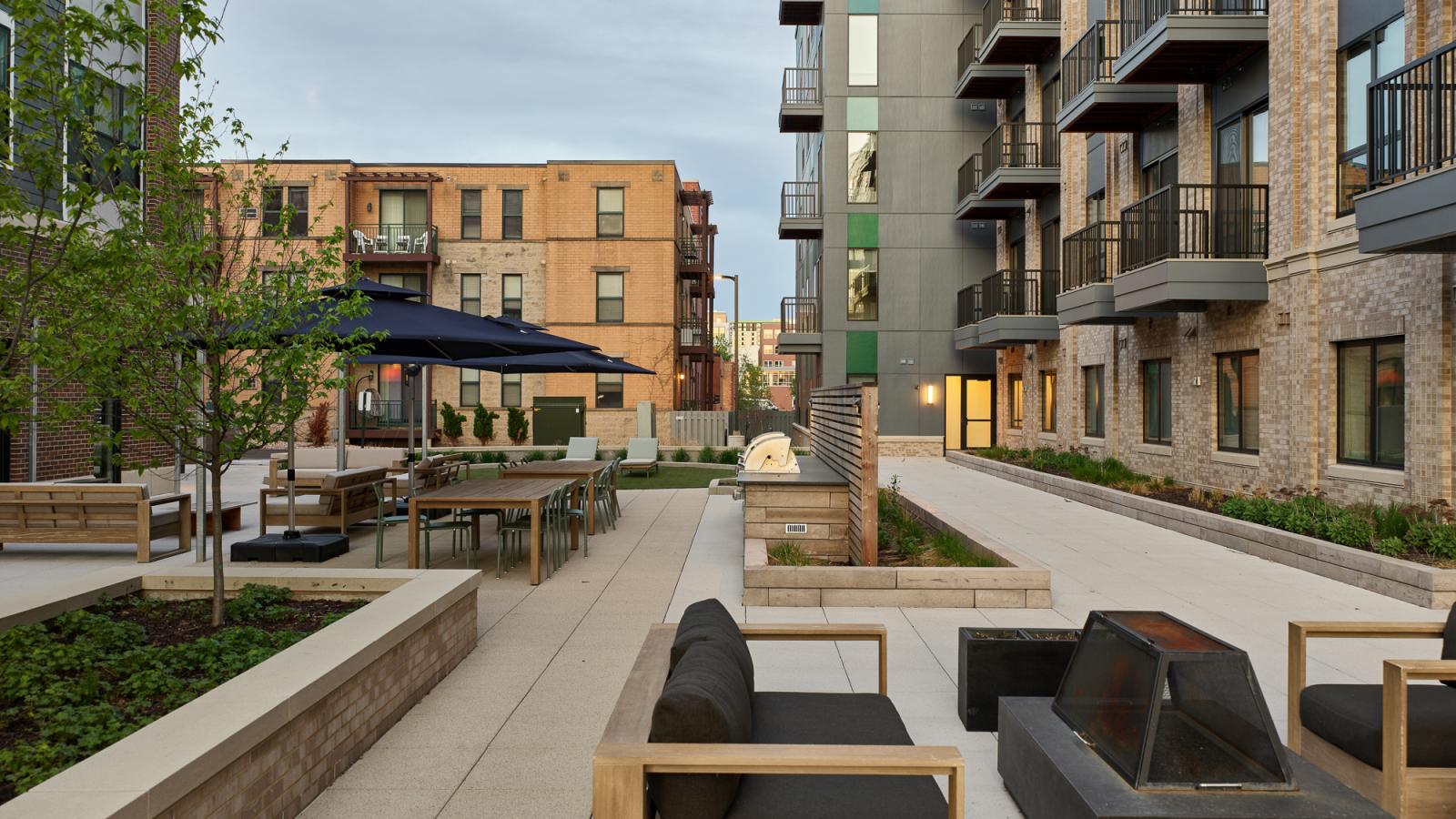 Landscaped courtyard at The Irwin featuring outdoor seating areas, gas grills, gathering spaces, and modern apartment surroundings in Madison’s Willy Street neighborhood.